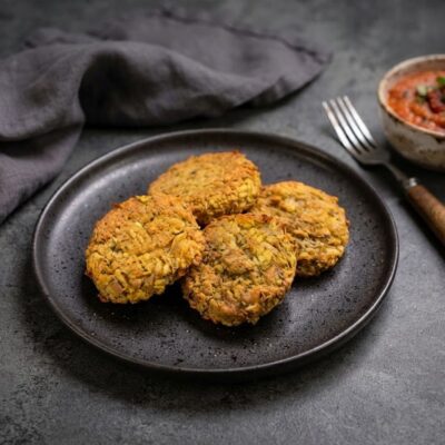 Zlatavé tofu karbanátky s mrkví a rýží podávané s rajčatovým dipem v keramické misce.